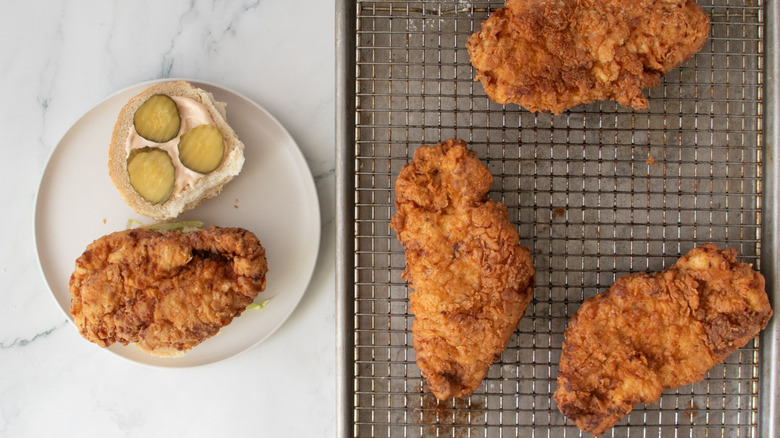 Fried chicken sandwich next to pieces of fried chicken