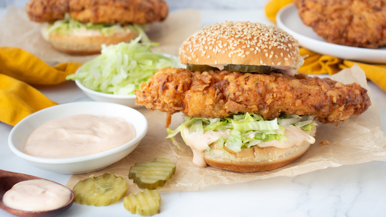 Fried chicken sandwich next to bowl of sauce
