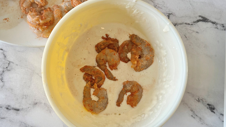Shrimp submerged into batter in bowl