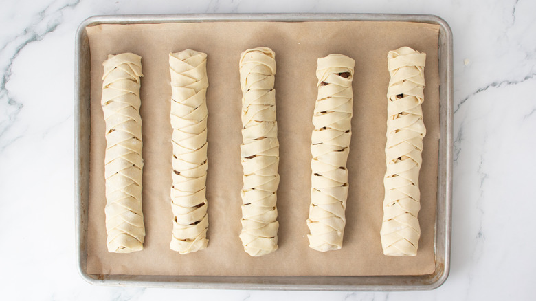 five braided pastry dough sticks in a pan