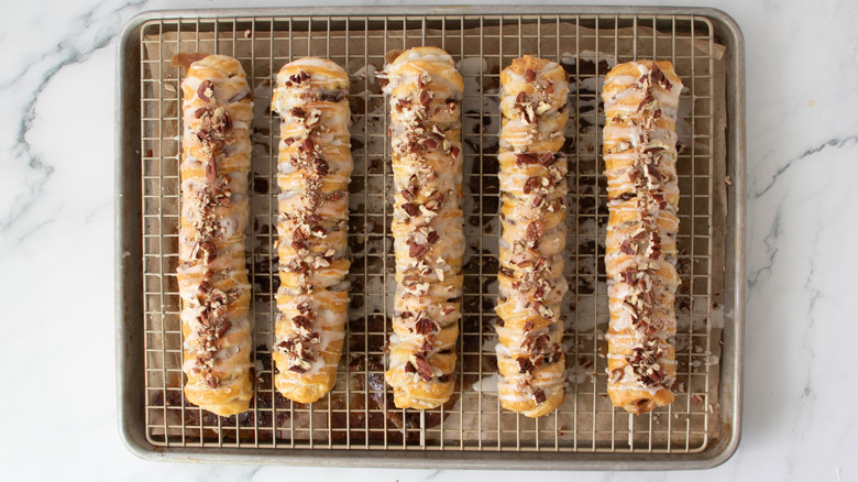 nut-topped braided pastry sticks on a wire rack