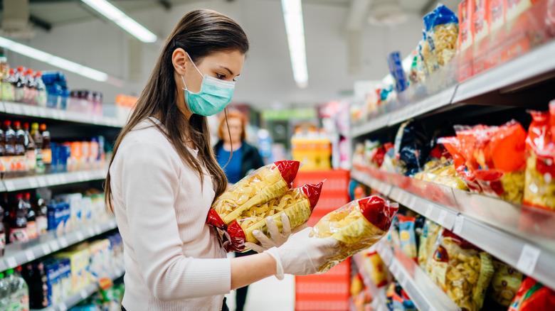 A woman wearing a mask selecting pasta