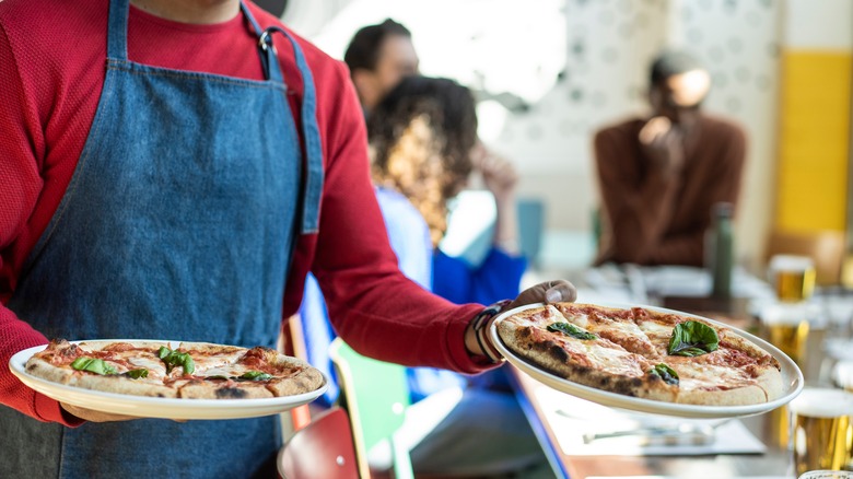 man serving pizzas