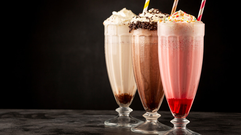 three milkshakes on black background