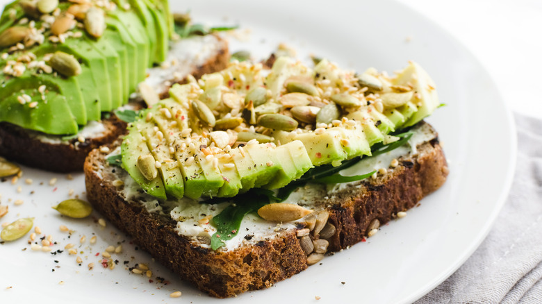 Toast with sliced avocado, butter, and seeds 