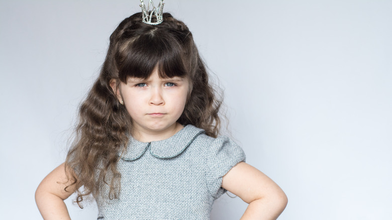 spoiled child with hands on hips and crown on head
