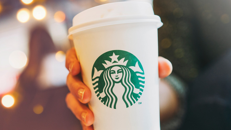 A hand holding a Starbucks cup