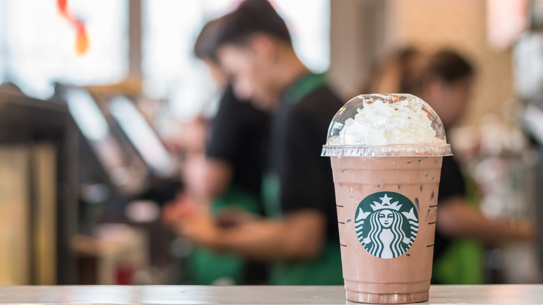 A frozen Starbucks drink with employees in the background