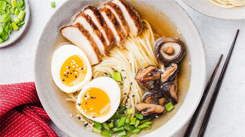 A bowl of ramen with meat, egg, and vegetables