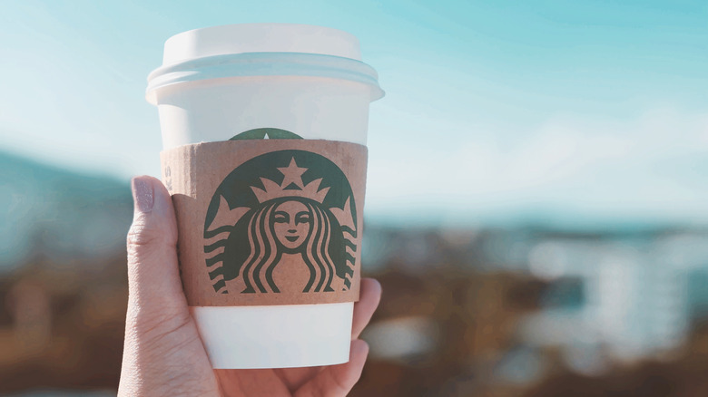 A hand holding a Starbucks cup