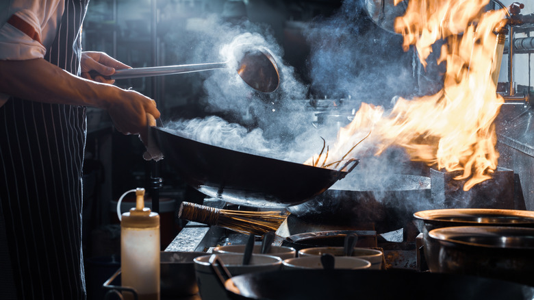 Chef stirring pan over flame