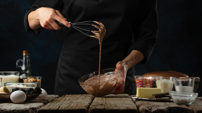 Person holding a whisk and mixing bowl