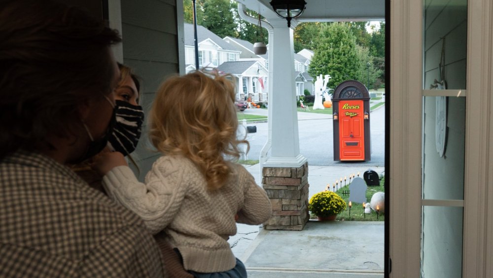 family wearing mask watching the Reese's Trick-or-Treat Door approach