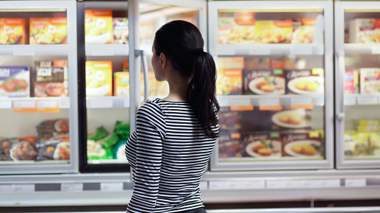 Person looking at options in the frozen food section of the grocery store