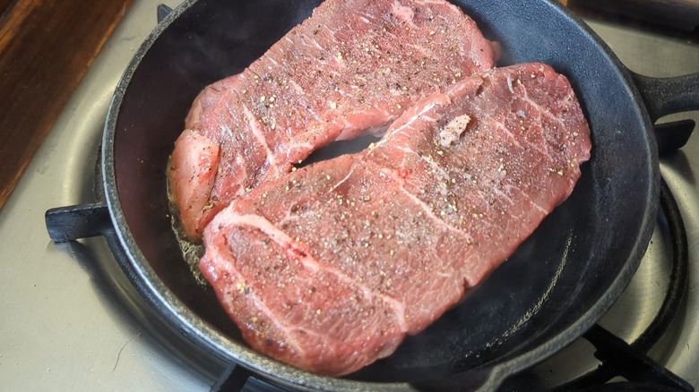 two seasoned sirloin steaks in small cast iron skillet