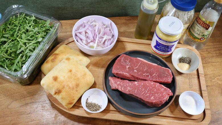 sirloin steak sandwich ingredients set out on wooden table