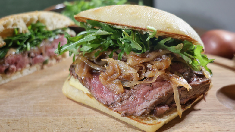 rare steak sandwich on ciabatta roll with creamy Dijonnaise sauce, caramelized shallots, and baby arugula