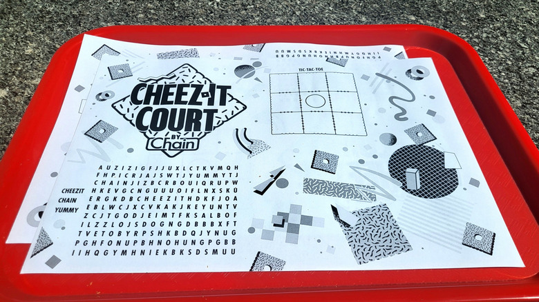A kids menu-style printout on a red tray, featuring the Cheez-It Court logo alongside a word search and a tic-tac-toe board.