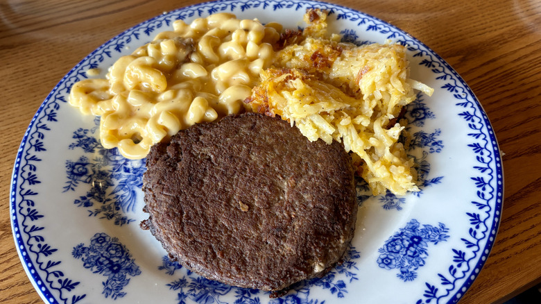 beef patty, mac and cheese, hashbrowns on decorative plate on table at Cracker Barrel
