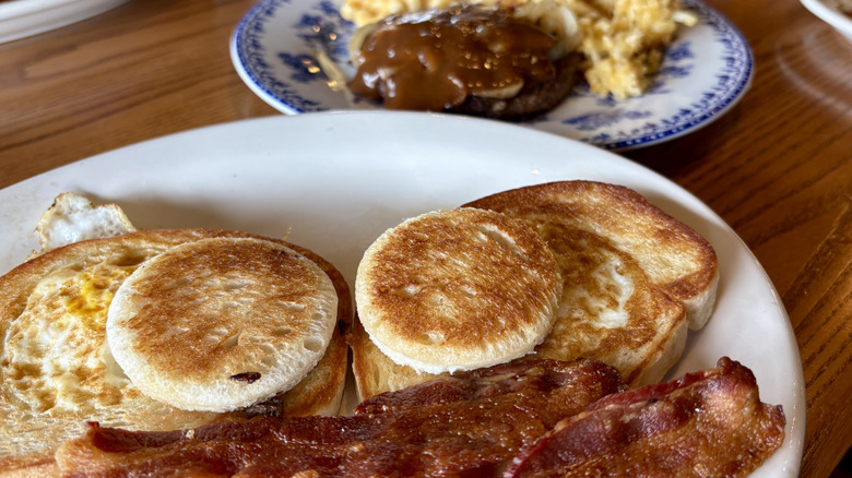 plate with toast, eggs, bacon in front of decorative plate with beef and gravy on table at Cracker Barrel
