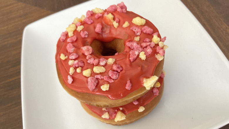 Two Dunkin' fruit punch donuts stacked on a white plate