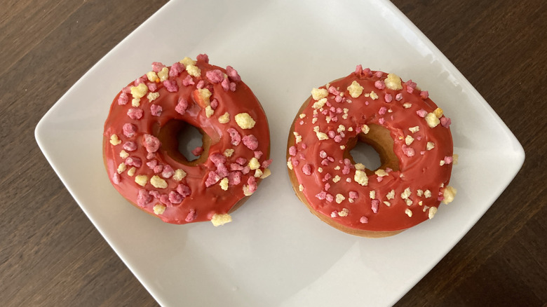 Two pink Dunkin' fruit punch donuts on a white plate