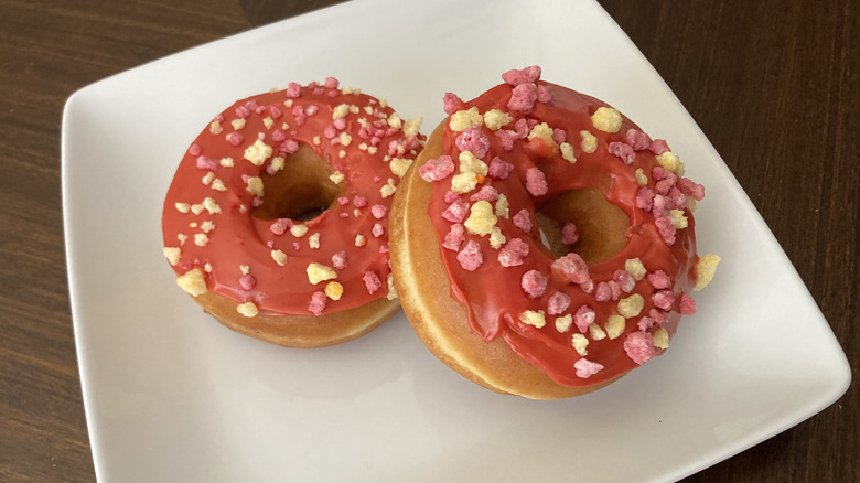 Two Dunkin' fruit punch donuts on a white plate