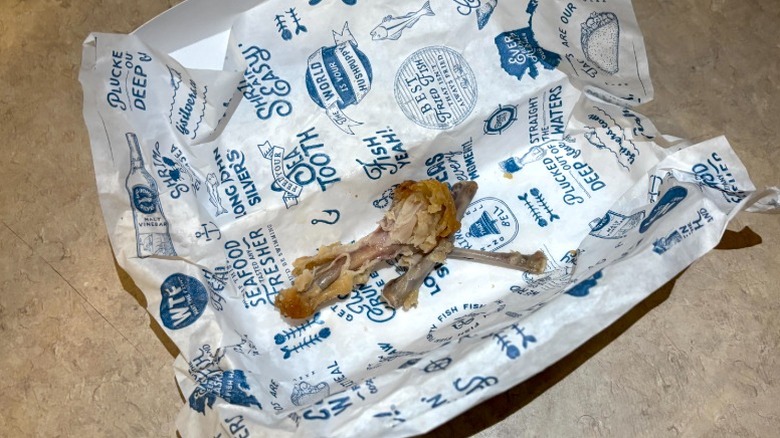 Branded Long John Silver's tissue paper with cleaned chicken wing bones in the middle on a neutral background