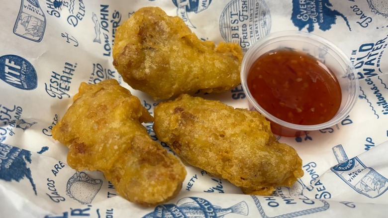 Three Crispy Battered Wings on a Long John Silver's branded paper with a side of sweet chili sauce