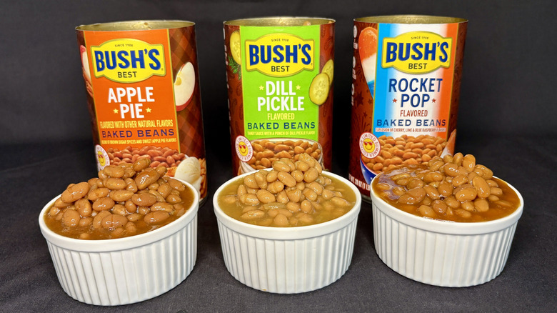 Cans of Bush's baked beans behind white dishes filled with beans