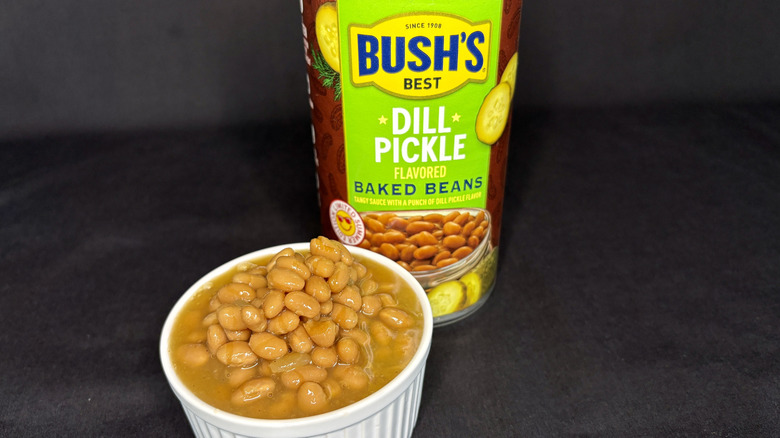 Bush's Dill Pickle Flavored baked beans can behind white dish filled with beans