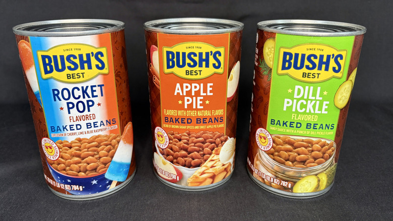 Three cans of Bush's baked beans on black background