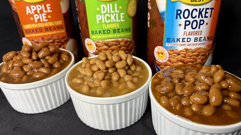 Cans of Bush's baked beans behind white dishes filled with beans