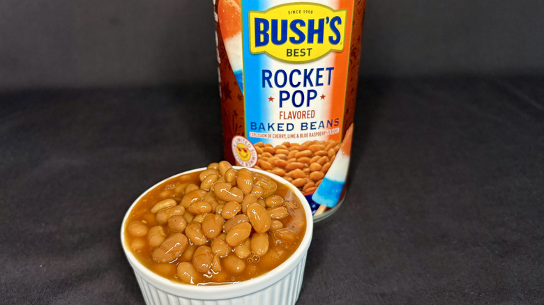 Bush's Rocket Pop Flavored baked beans can behind white dish filled with beans
