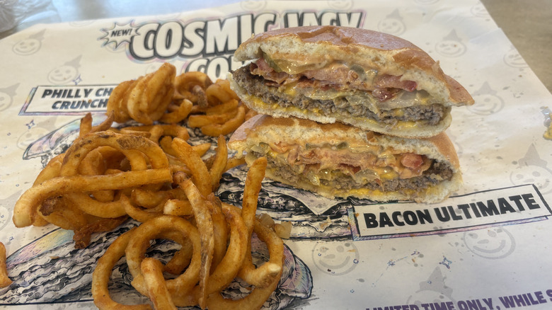 A Bacon Ultimate Cosmic Jack cut in half on a plate with curly fries