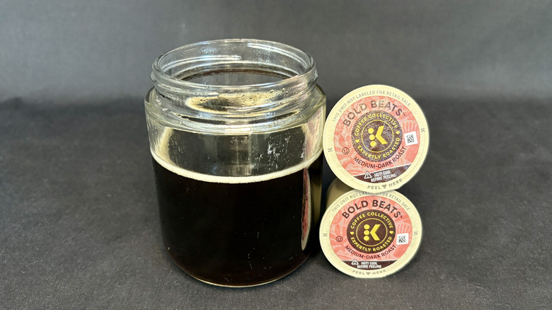 Coffee in a clear glass next to stacked K-Cups