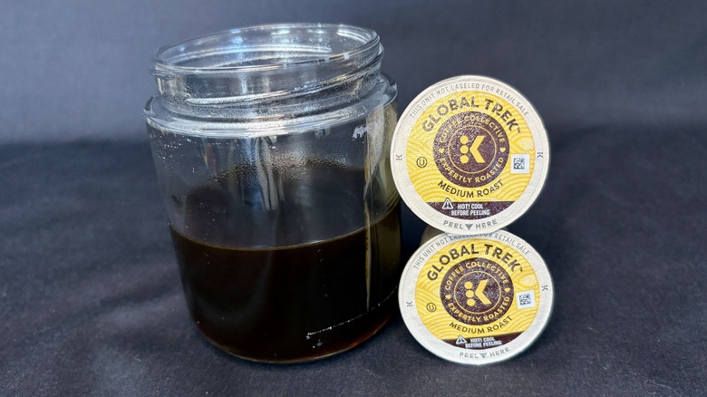 Coffee in a clear glass next to stacked K-Cups