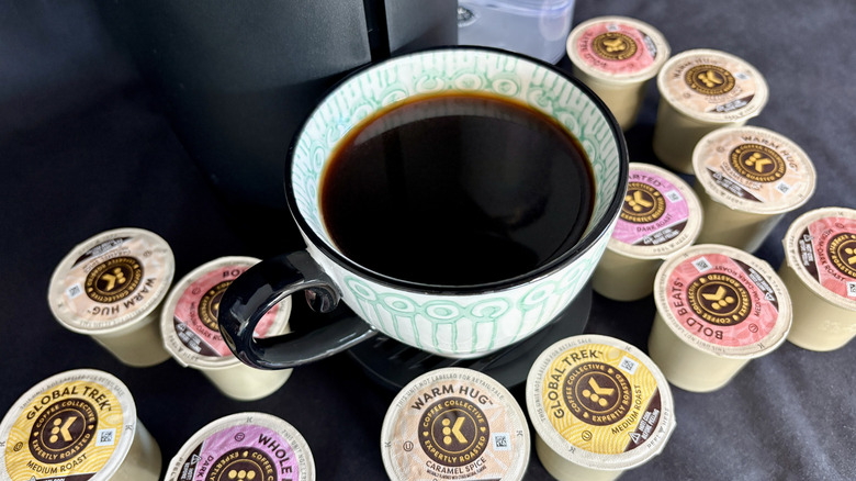 A close-up of a cup of coffee on a Keurig machine surrounded by K-cups