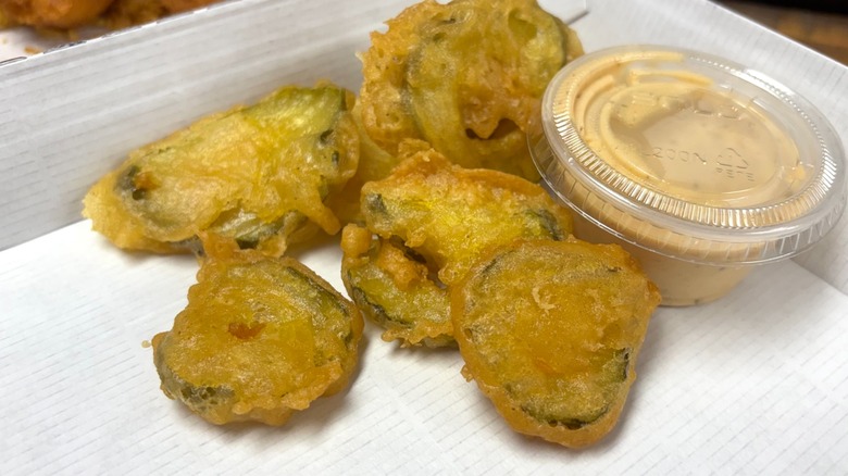 A close-up of Long John Silver's fried pickles with a side of Ranch with Old Bay in a box