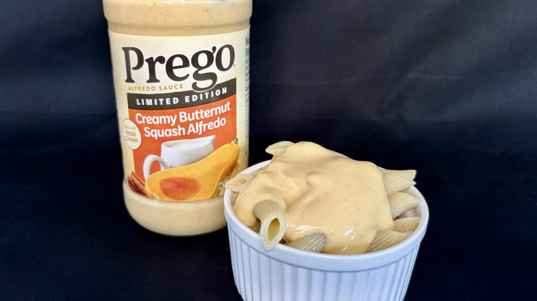 A jar of Prego Creamy Butternut Squash Alfredo Sauce with dish of pasta with sauce in front