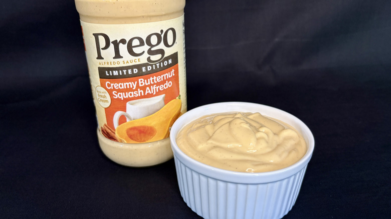 A jar of Prego Creamy Butternut Squash Alfredo Sauce with dish of sauce in front