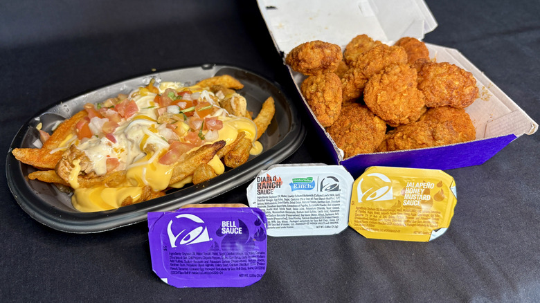 Taco Bell Diablo Dusted Crispy Chicken Nuggets, Zab's Chicken Ranch Nacho Fries, and three dipping sauces on a black background