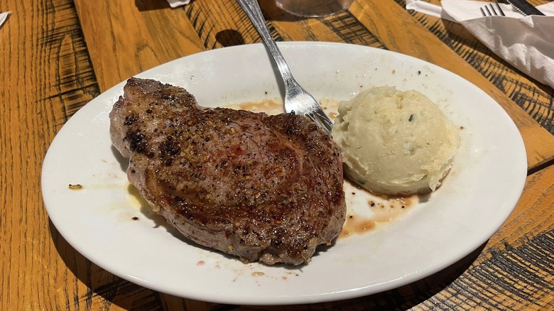 Ribeye steak on white plate with mashed potatoes
