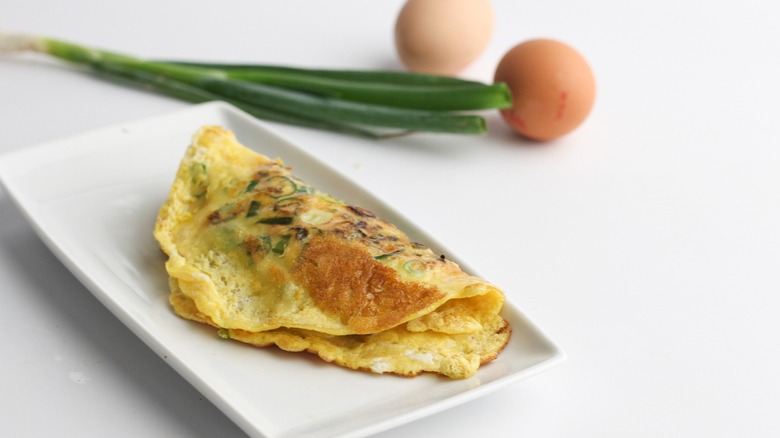 rice paper omelette on plate with egg and scallion in background