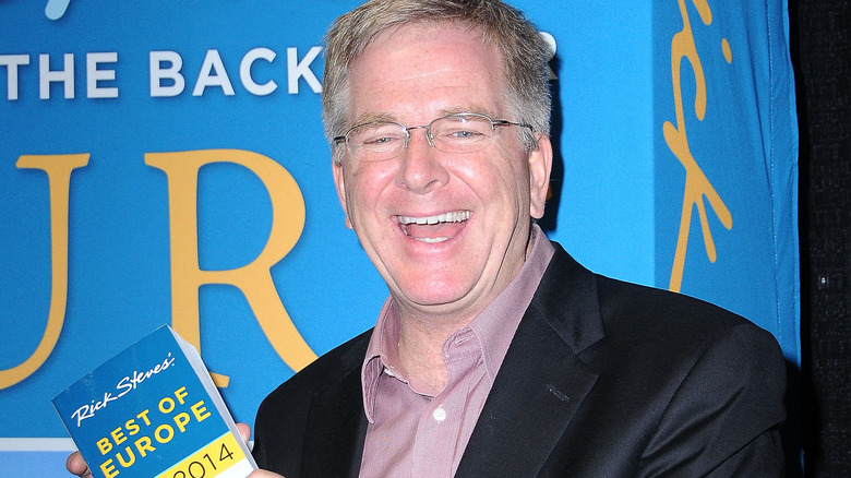 Rick Steves laughing, holding book