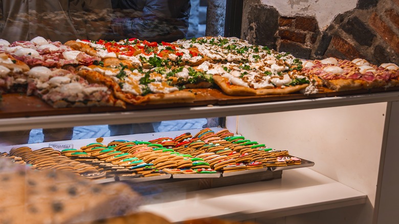 Assortment of pizzas and cookies in shop window