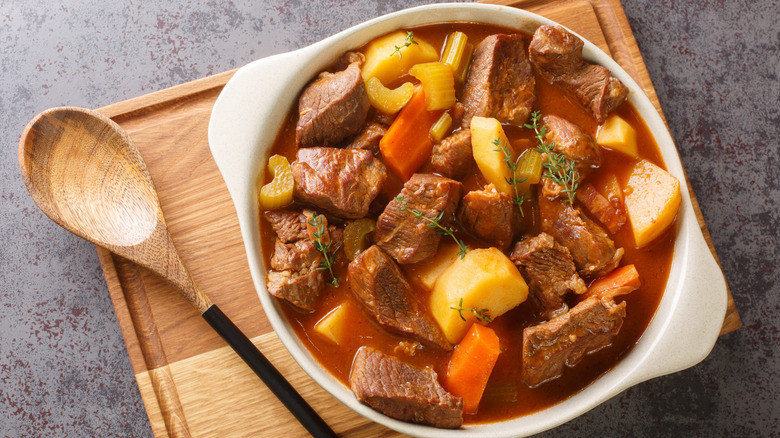 Hearty Irish inspired beef stew made with garlic, stock, Guinness, bacon, potatoes, carrots, and onions closeup in the pot on the table.