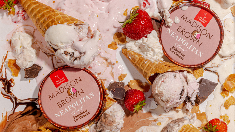Cones of Madison Brown Neapolitan ice cream surrounded by melted ice cream, strawberries, chocolate, and ice cream carton lids