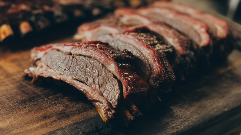 A close-up of cooked beef ribs on a cutting board.