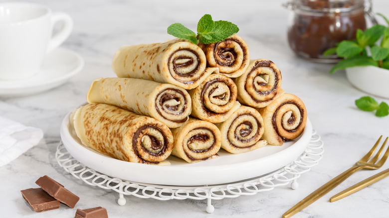 Nine rolled crepes on a plate